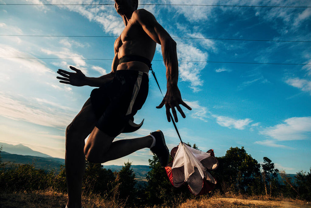 Paraşütlü sağlıklı bir sporcunun portresi mavi gökyüzünde doğa da koşuyor. - Fotoğraf, Görsel