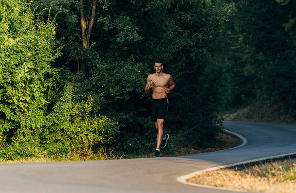 Mountain trail μαραθώνιος τρέχει άνθρωπος κατάρτισης για την καλή φυσική κατάσταση και υγιεινό τρόπο ζωής, ενώ τρέχει με ακουστικά - Φωτογραφία, εικόνα