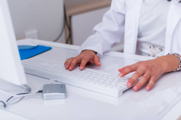 Close up hands of a female physician ( nurse ) typing on her whi - Foto, afbeelding