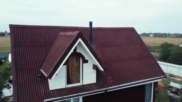 Vista aérea de la casa de campo de lujo con techo rojo en el asentamiento de la casa cerca del campo vacío para la futura construcción en verano contra el cielo azul nublado. Imágenes de archivo. Hermoso paisaje rural
 - Metraje, vídeo