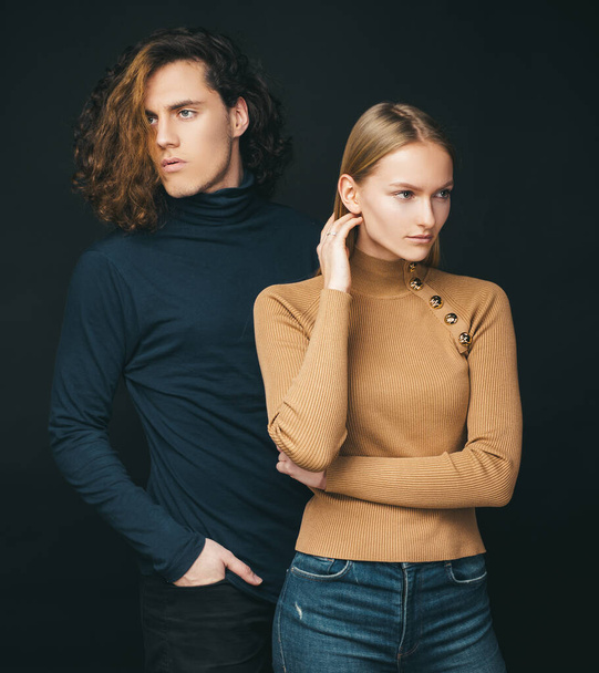 Concentrated girl standing next to a curly boyfriend. Attractive couple together. The beginning of life of a young couple. The first joint family decisions. Warm colors in clothing. - Foto, afbeelding