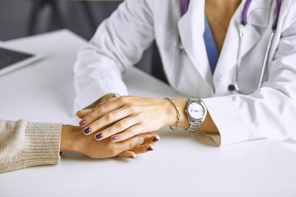Γυναίκα γιατρός ηρεμεί ασθενή και κρατά το χέρι - Φωτογραφία, εικόνα