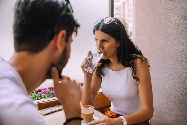 若いカップルがカフェに座って朝のコーヒーを飲んで楽しい会話をしています - 写真・画像