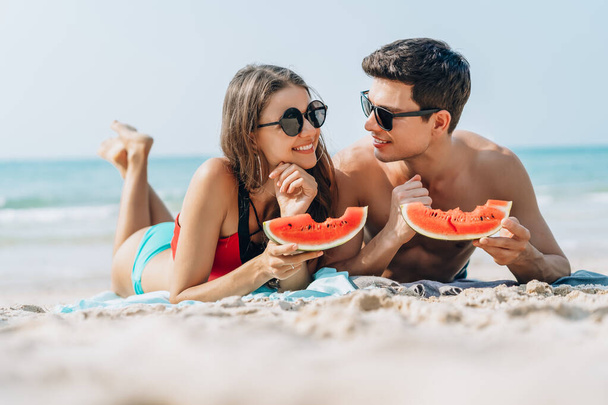 Onnellinen nuori pari tilalla ja syö viipaleita vesimelonia th
 - Valokuva, kuva