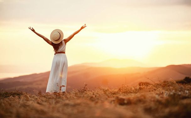 Onnellinen nainen seisoo selkä auringonlaskussa luonnossa
  - Valokuva, kuva