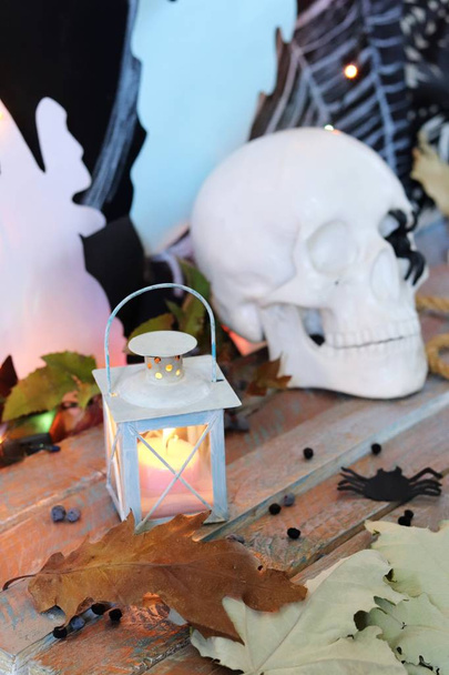 Teschio, arredamento mistico, illuminazione, lanterna decorativa, foglie autunnali su un tavolo di legno, interno per Halloween, ottobre
 - Foto, immagini