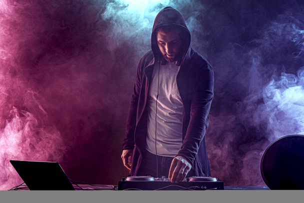 Trendy male dj posing against mixing console - Фото, зображення