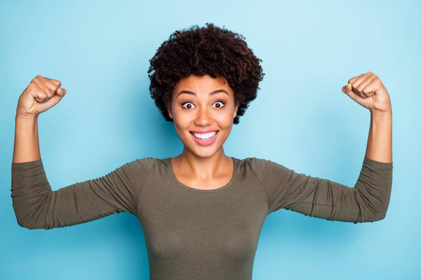 Portrait of amazed crazy mulatto girl show muscles impressed by her power scream wow omg wear casual style clothes isolated over blue color background - Photo, Image