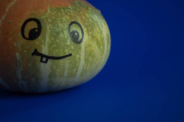 Pumpkin with a funny face painted on a bright background - Fotoğraf, Görsel