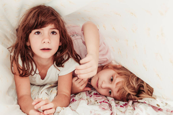 Aranyos kislányok, nővérek ébrednek fel reggel. Gyerekek pizsamában, alszanak. - Fotó, kép