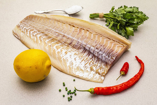 Raw cod loin fillet with lemon, sea salt, chili and cayenne pepper, parsley - Photo, Image
