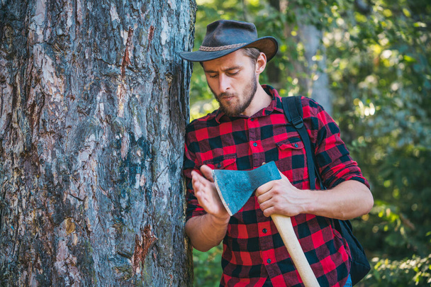 Lumberjack worker walking in the forest with axe. Deforestation is a major cause of land degradation and destabilization of natural ecosystems. - Φωτογραφία, εικόνα