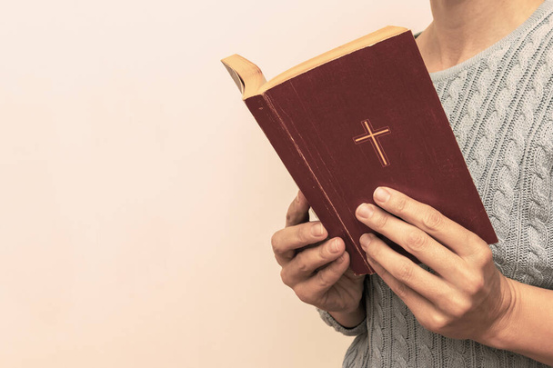 Young praying christian woman's hands holding holy bible with a cross on a cover - Фото, зображення