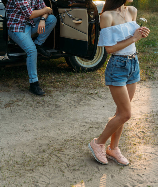 a girl with a flower and in a white blouse, a man in a plaid shirt is sitting on the back of the car seat, waiting - Photo, image