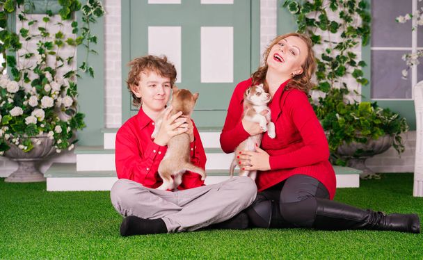 Happy maminka a syn pózovat na zelené trávě se dvěma roztomilé malé husky štěňátka - Fotografie, Obrázek