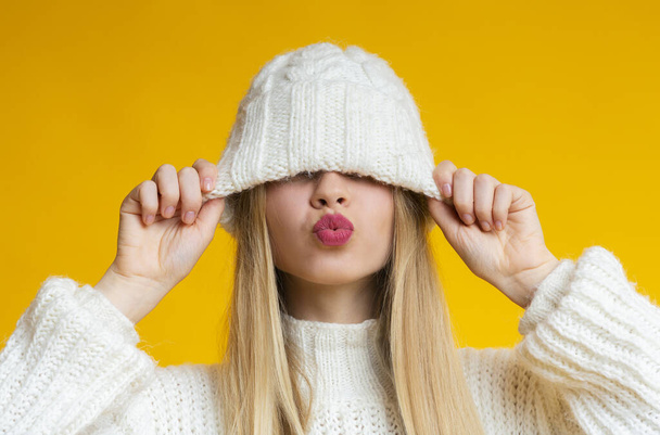 Woman with kissing lips pulling down woollen hat - Valokuva, kuva