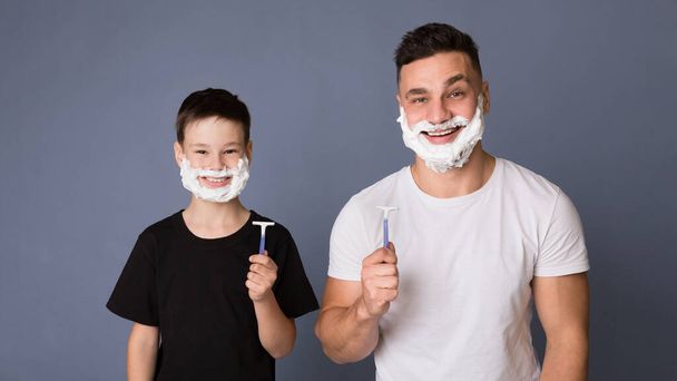 Dad teaching his teen son how shave, standing with razors and shaving foam - Photo, Image