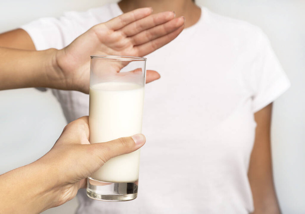 Unerkennbares Mädchen, das Nein zu Milchglas gestikuliert, weißer Hintergrund, abgeschnitten - Foto, Bild