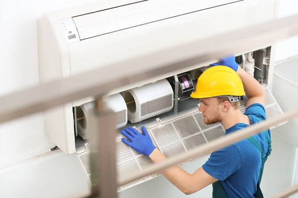 Professional technician maintaining modern air conditioner indoors - Photo, image