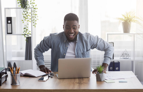 Radostný černošky zaměstnanec při pohledu na obrazovce notebooku s vzrušením - Fotografie, Obrázek