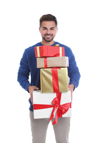 Happy young man holding Christmas gifts on white background - Photo, image