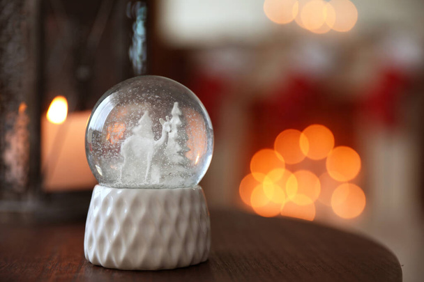 Snow globe on wooden table against blurred background, space for text. Bokeh effect - Foto, immagini