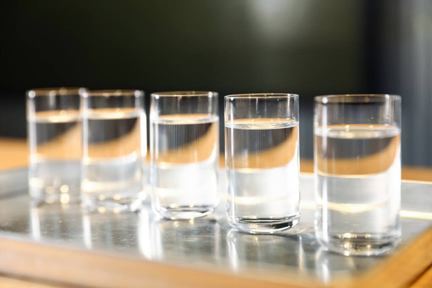 Shots of vodka on bar counter against dark background, closeup - Фото, изображение