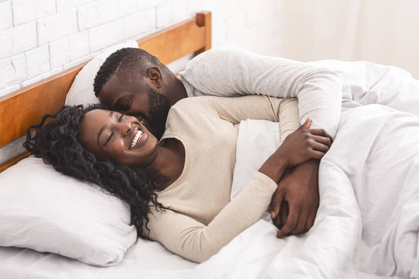 Young black couple waking up in bed in the morning - 写真・画像