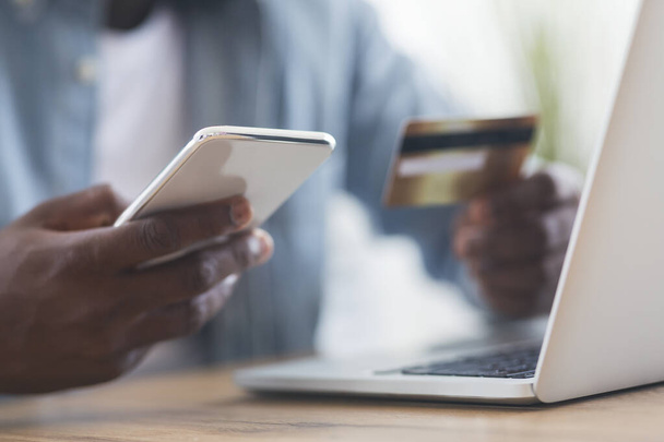 Nierozpoznawalny czarny mężczyzna za pomocą smartfona i karty kredytowej, zakupy online - Zdjęcie, obraz