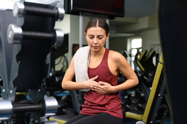 Young woman having heart attack in gym - Fotó, kép