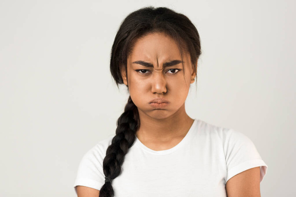 Θυμωμένη Αφρικάνα που φυσάει τα μάγουλά της, γκρι φόντο - Φωτογραφία, εικόνα