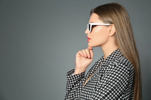 Young woman wearing stylish sunglasses on grey background. Space for text - Photo, Image