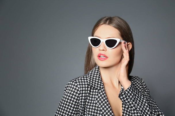 Young woman wearing stylish sunglasses on grey background. Space for text - Zdjęcie, obraz