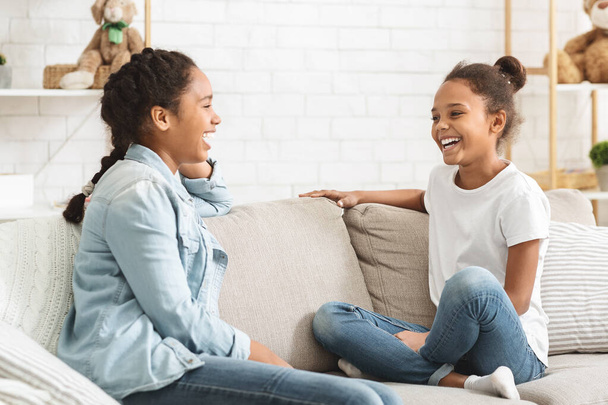 Dwie słodkie dziewczyny siedzą na kanapie w domu i rozmawiają - Zdjęcie, obraz