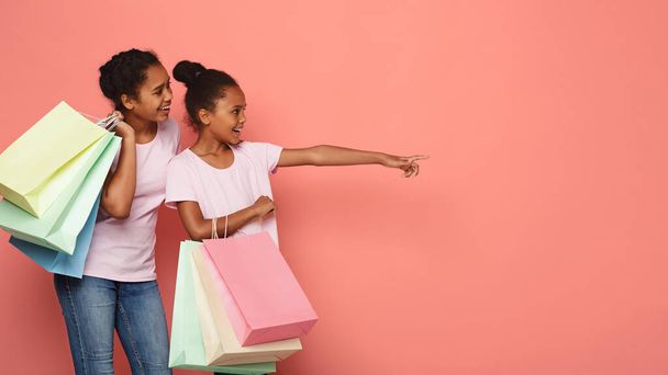 interessierte afrikanische Mädchen mit Einkaufstüten, die auf leeren Raum zeigen - Foto, Bild