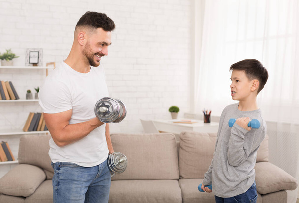 Onnellinen isä ja poika harjoittelemassa käsipainoilla kotona
 - Valokuva, kuva
