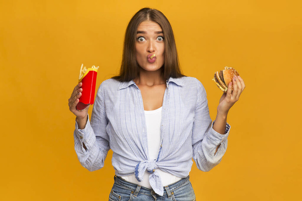 Surprised Woman Eating Burger And French Fries, Studio Shot - 写真・画像