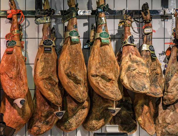 Piernas enteras de jamón serrano iberico en exhibición en un mercado local en Madrid, España
 - Foto, Imagen