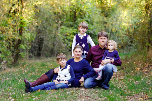 Portrait of young parents with three children. Mother, father, two kids brothers boys and little cute toddler sister girl having fun together in autumn forest. Happy family of five - Fotó, kép