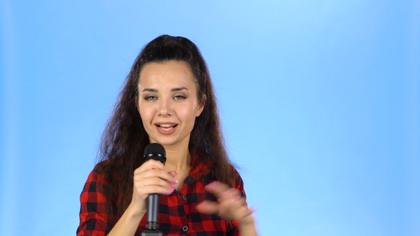 Dame singt in einem Studio auf blauem Hintergrund ins Mikrofon - Filmmaterial, Video