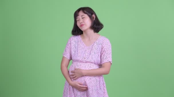 Блаженна азіатська вагітна жінка розслабляється з закритими очима. - Кадри, відео