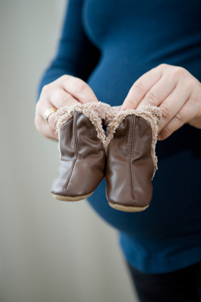 Pregnant mother holding baby booties - Fotoğraf, Görsel