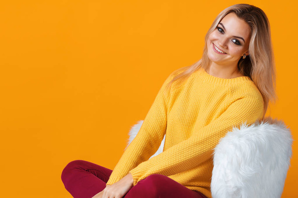 Happy and cheerful blonde in a yellow sweater on a yellow background. Positive young woman - Fotografie, Obrázek