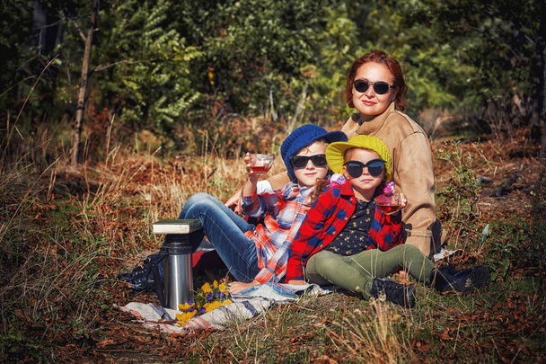 Children on vacation in nature on an autumn day . Camping in the woods . Family holiday. Children in comfortable clothes for walking and relaxing - Fotó, kép