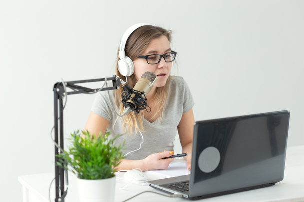 Radio host, streamer and blogger concept - Woman working as radio host at radio station sitting in front of microphone - Foto, afbeelding