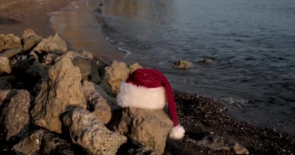 Tropikal kumlu sahilde sakin dalgalarla Noel Baba şapkası. Kış tatili Adada yeni yıl kutlaması. Kavram - Video, Çekim