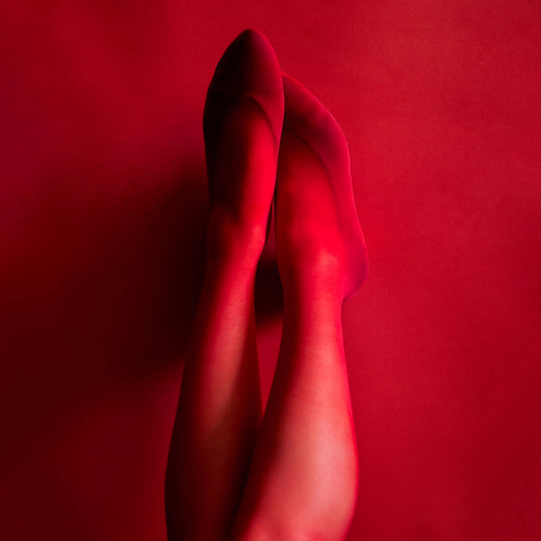 photo female legs up in red tights on a red background - Photo, Image