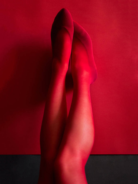 foto pernas femininas até em meias vermelhas com um fundo vermelho
 - Foto, Imagem