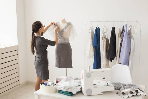 Dressmaker, tailor, fashion and showroom concept - Side view of female fashion designer measuring materials on mannequin in office - Foto, Imagem
