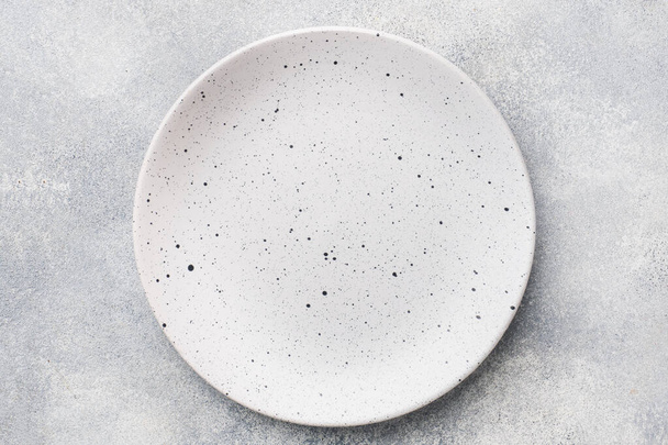 Empty ceramic plate on a light concrete background. Top view. - Foto, Imagem